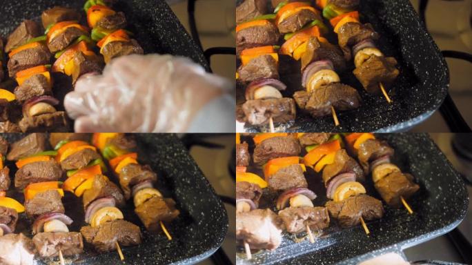 腌制的牛肉串和在烤架上准备的蔬菜。厨师把肉煎到其他地方