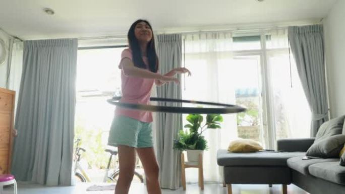 亚洲女孩在家里的窗户附近玩呼啦圈，积极的生活方式理念。