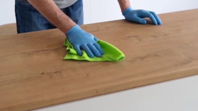 男子戴着蓝色橡胶防护手套，清洁木制厨房台面。慢动作