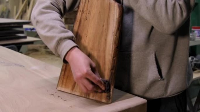 木匠用保护性亚麻籽油涂覆木制切菜板的特写