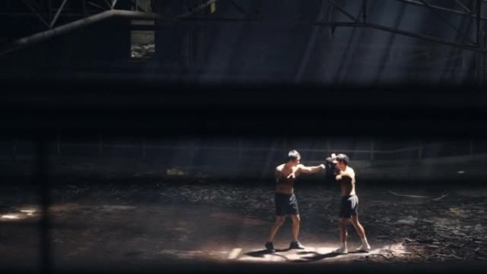 4k亚洲男子拳击手在废弃的建筑里和男教练一起练习拳击。