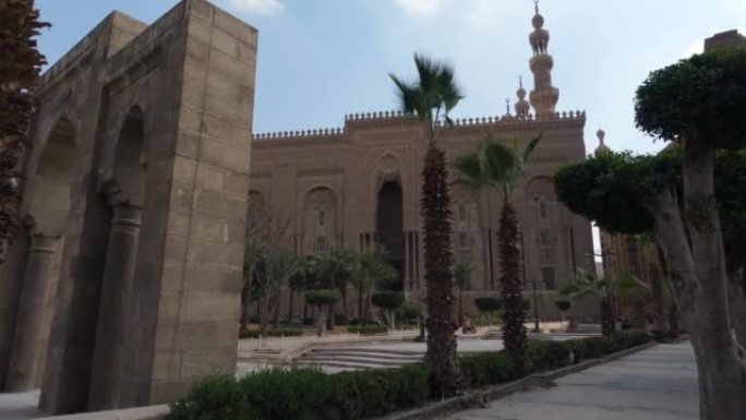 苏丹哈桑的伊斯兰学校外，棕榈树和游客站在旁边。开罗,埃及。手持式视图