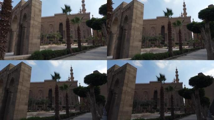 苏丹哈桑的伊斯兰学校外，棕榈树和游客站在旁边。开罗,埃及。手持式视图
