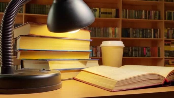 书籍、咖啡和灯在图书馆的桌子上旋转，在黑暗的房间里的书架上旋转