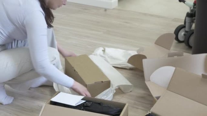 女人在家里拆箱纸箱，从网上商店交付带有新旅行袋的包裹。