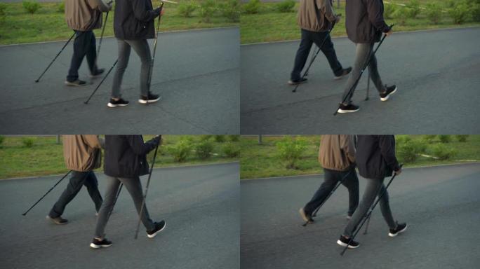 养老金领取者在公园里从事北欧散步。一个男人和一个女人用棍子走路来改善健康。腿靠近。