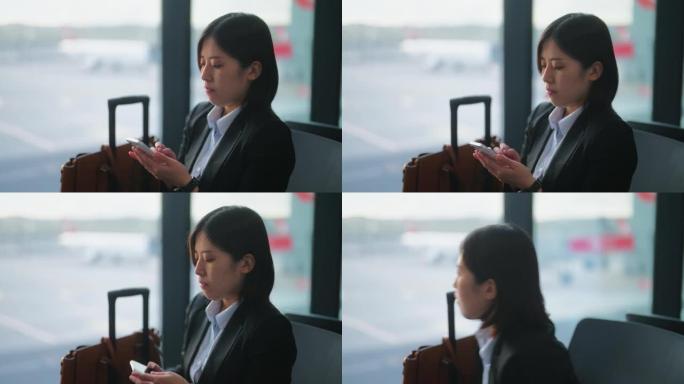女商人在机场等航班时使用智能手机。商务旅行