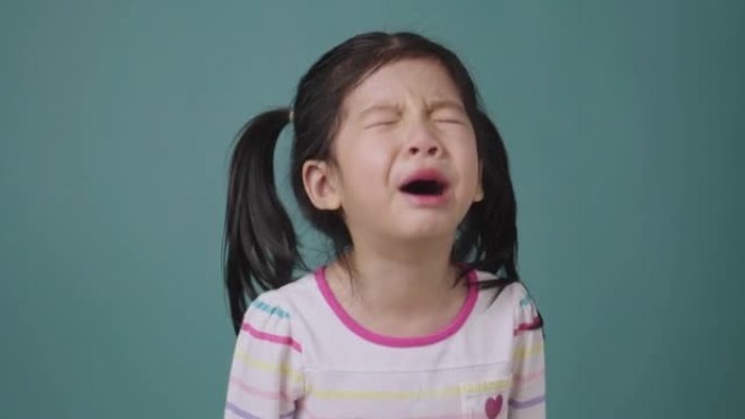 亚洲小女孩哭泣的肖像在蓝色背景上泪流满面，学校孩子的教育理念
