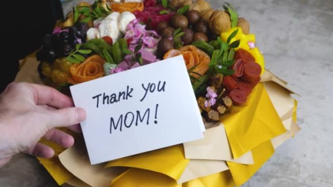 成年儿子祝贺妈妈送了一束鲜花和一封信，说谢谢妈妈。妈妈的生日，礼物甜蜜的花束。感谢卡谢谢妈妈
