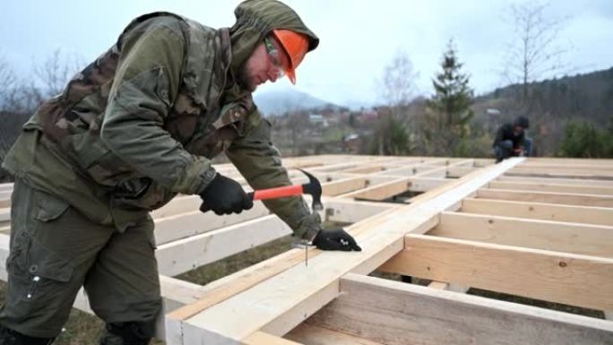 男子工人在建造木结构房屋时锤击。
