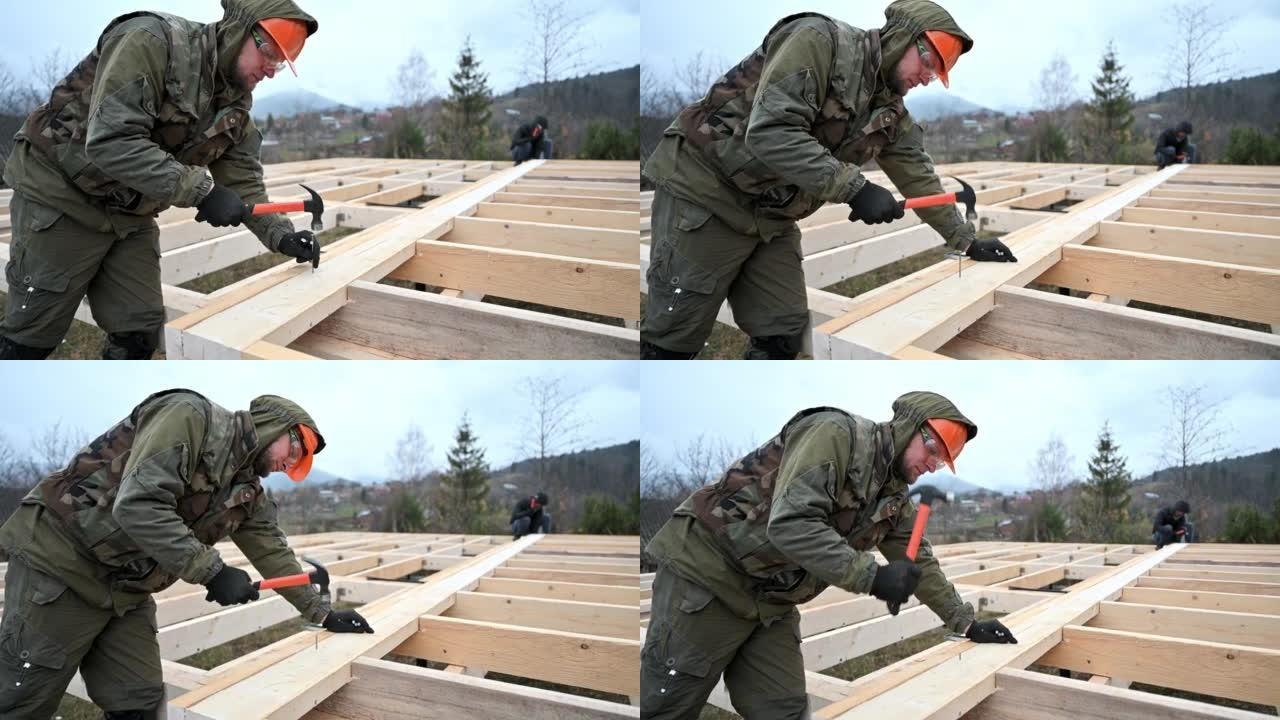 男子工人在建造木结构房屋时锤击。