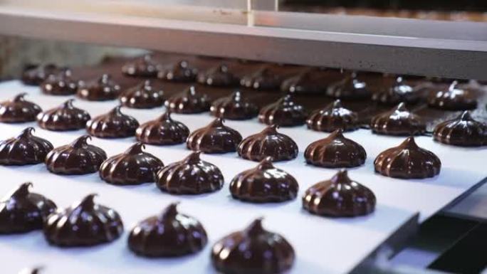 覆盖着巧克力的甜点从传送带网格移动到传送带。新鲜制作的和风甜点特写。