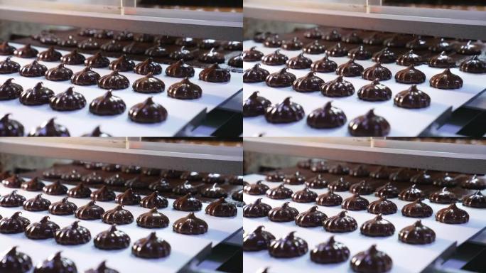 覆盖着巧克力的甜点从传送带网格移动到传送带。新鲜制作的和风甜点特写。