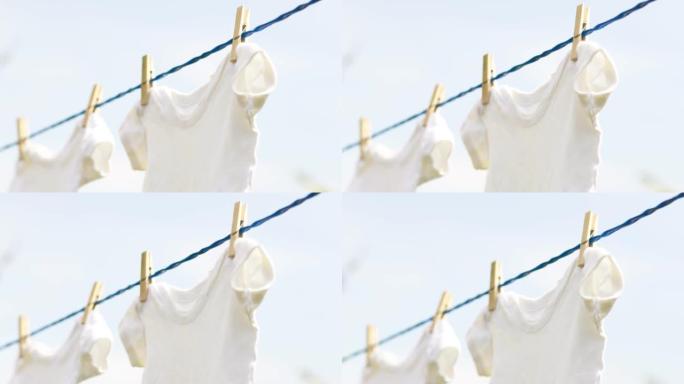 春日户外挂在绳子上的白色婴儿衣服。
