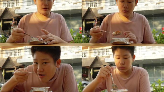 亚洲男孩在泰国华欣的露天街头美食餐厅与家人共进早餐。