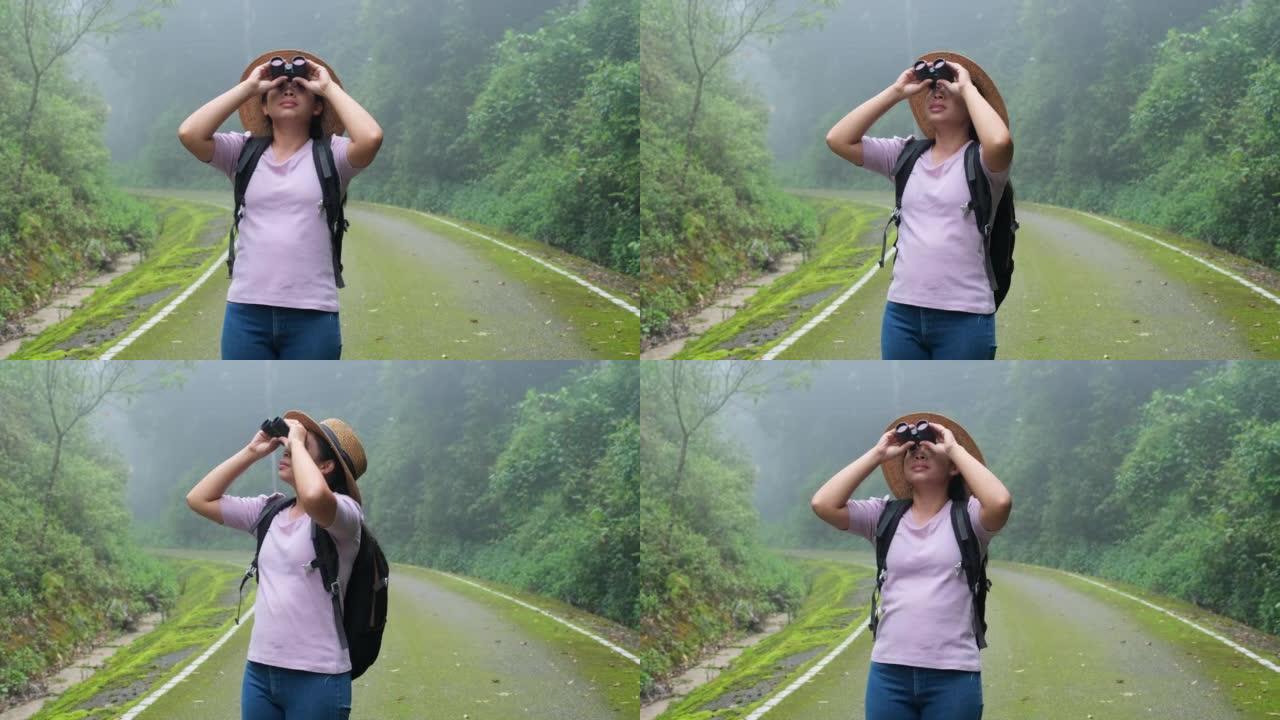 女性环保主义者在雨林中使用双筒望远镜。女探险家使用双筒望远镜旅行，并拥有幸福的微笑。游客透过双筒望远