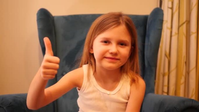 小女孩的脸肖像让竖起大拇指的手势坐在椅子上看着镜头和微笑