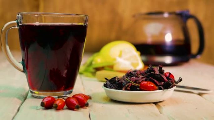 在木板上的透明杯子中的红茶，玫瑰果酊，由红色浆果制成的顺势疗法药茶