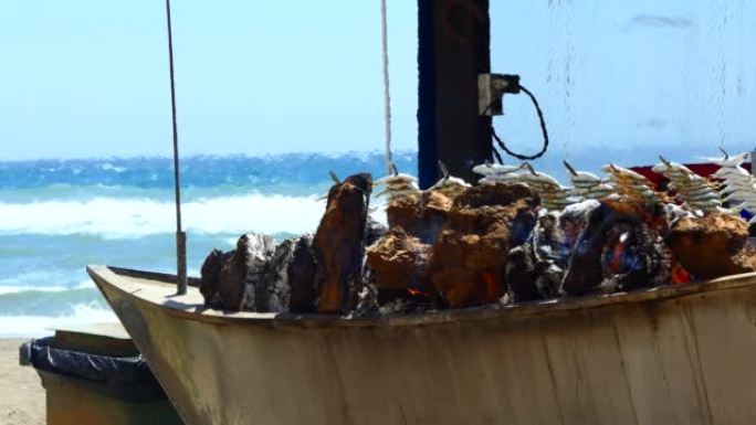 海滩边在木船烧烤烤架上烹饪新鲜鱼