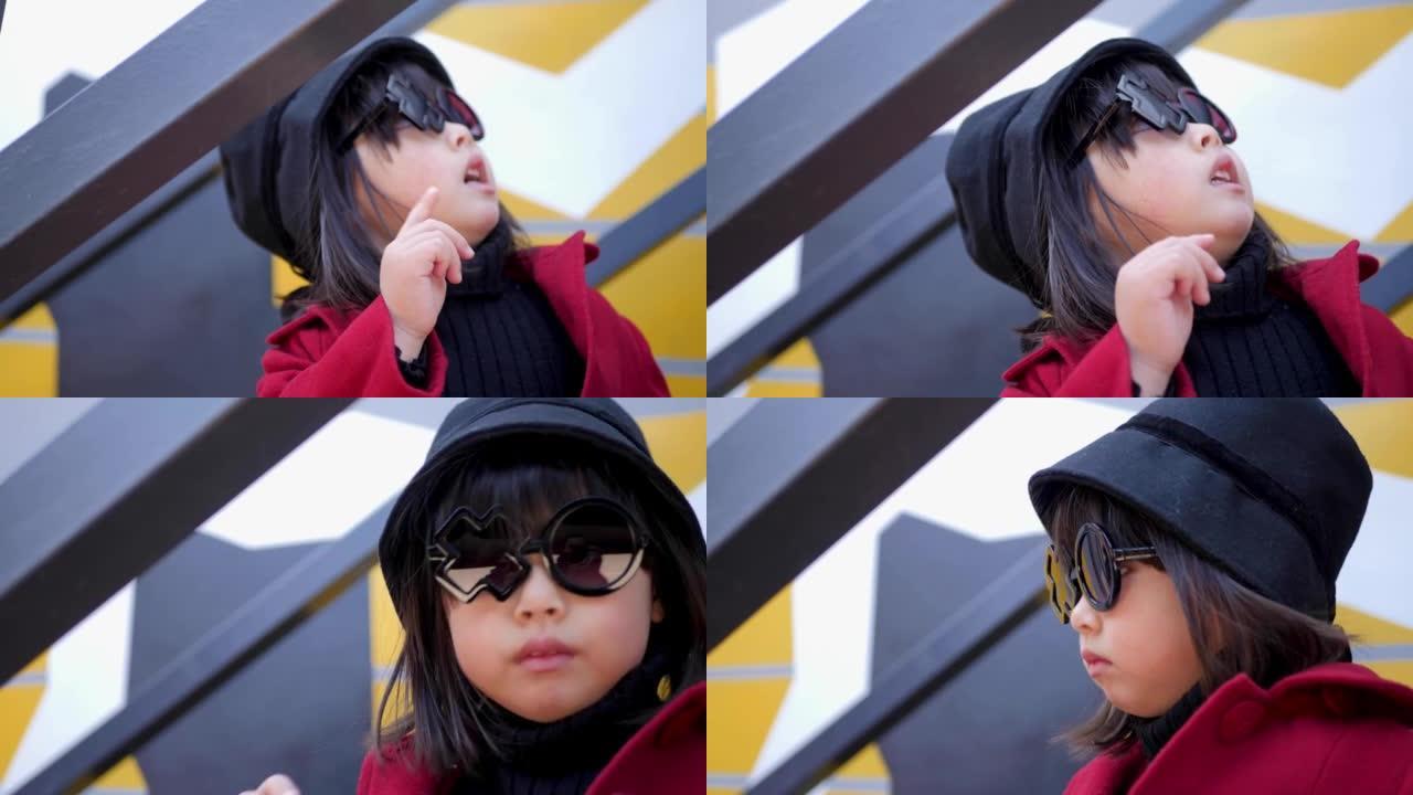 穿着红色外套，帽子和圆形眼镜的韩国女孩坐在秋天的铁楼梯上