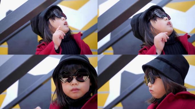 穿着红色外套，帽子和圆形眼镜的韩国女孩坐在秋天的铁楼梯上