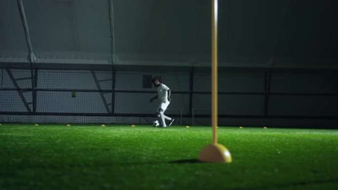 成年足球运动员夜间在人造草的足球场训练，练习运球