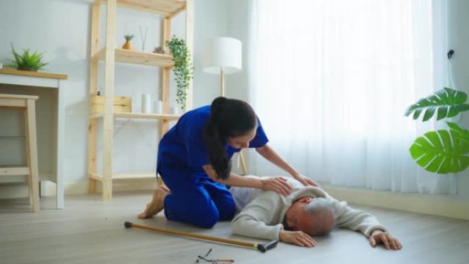 亚洲护理人员帮助老年男性在家中摔倒。老年老年患者在做物理治疗后发生事故，然后由客厅有吸引力的治疗师护