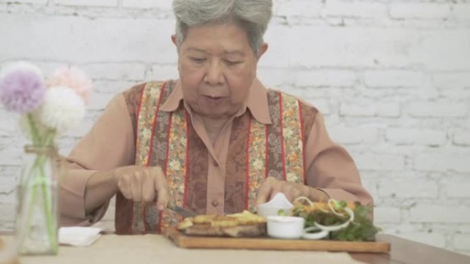 老年老年妇女吃烤猪排牛排食物。成熟的退休生活方式