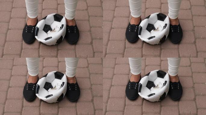 泄了气的眼泪足球放在女孩鞋之间，瓷砖路面