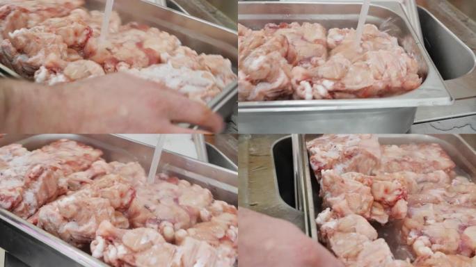 使用温热的自来水在工业容器中解冻鸡翅和鸡腿的过程。快速解冻。快餐店腌制鸡肉的过程。
