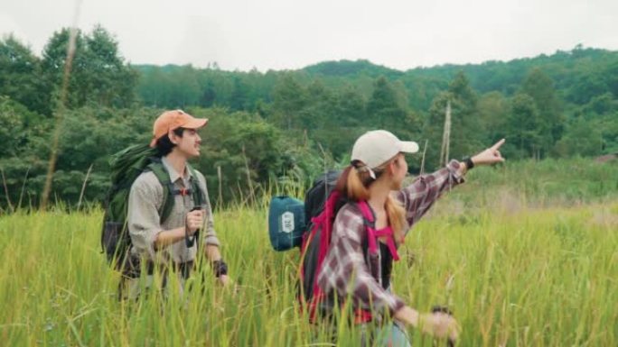 快乐的年轻夫妇徒步旅行者走过一片干燥的草地。年轻的男人和女人一起享受美好的时光。