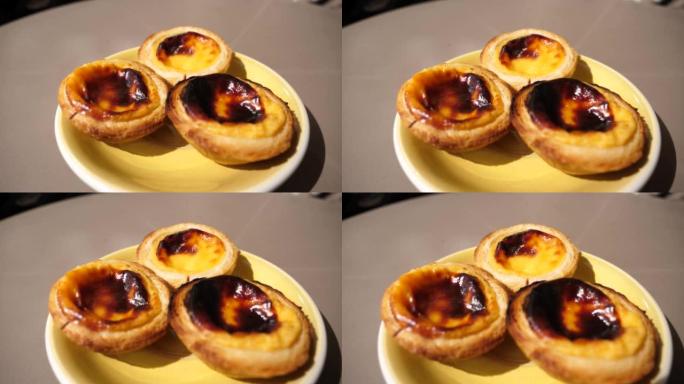 餐厅餐桌上的三个 “pastel de nata” 甜葡萄牙糕点食品的一部分