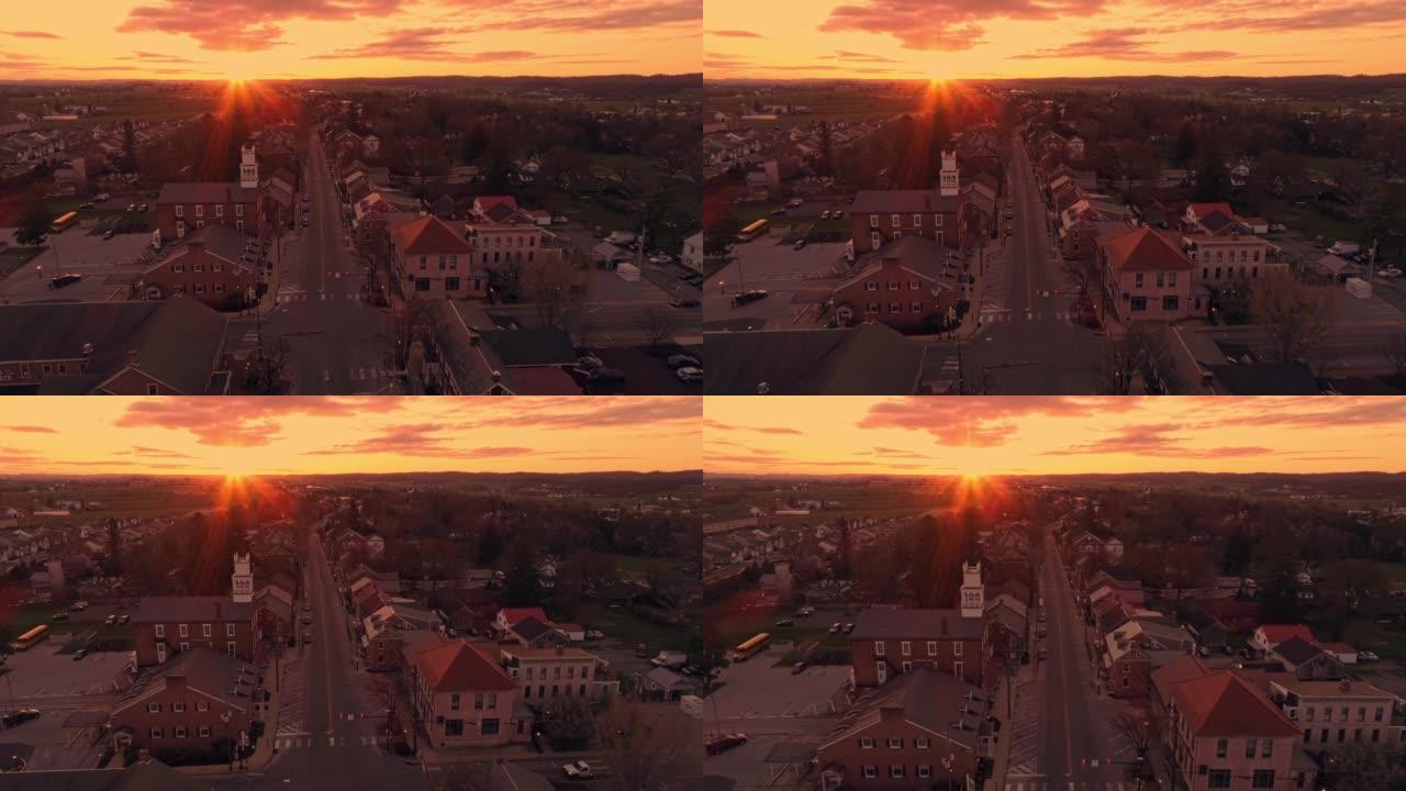 春天的日出时，太阳打破了地平线，一个小镇沿着主要街道行驶的高鸟瞰图
