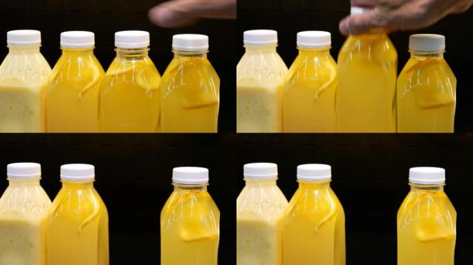 带有天然柑橘汁的塑料瓶的特写镜头和一只男性的手