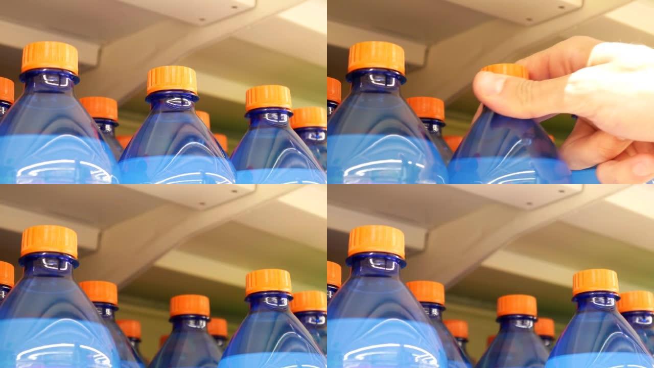 商店货架上蓝橙色塑料瓶汽水的特写镜头，一名男性买家拿走了一个