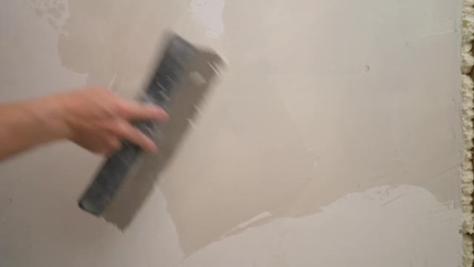 抹灰器在粘贴墙纸之前先将墙壁拉平。用腻子平整墙体的过程