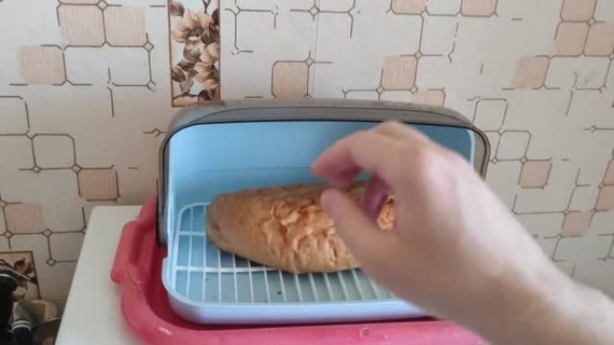 男人把面包放在面包盒里，盖上盖子