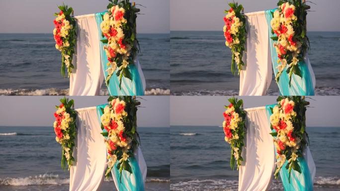 户外美丽的夏季婚礼。海上用浅色布和白色和粉红色花朵制成的婚礼拱门