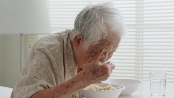 资深亚裔女子白发在疗养院吃食物