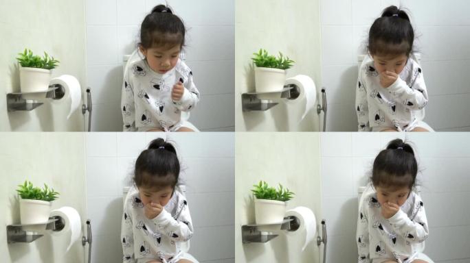 亚洲小女孩坐在白色浴室的抽水马桶上，学习如何自己使用马桶，为父母教孩子，KidsHealth概念，慢