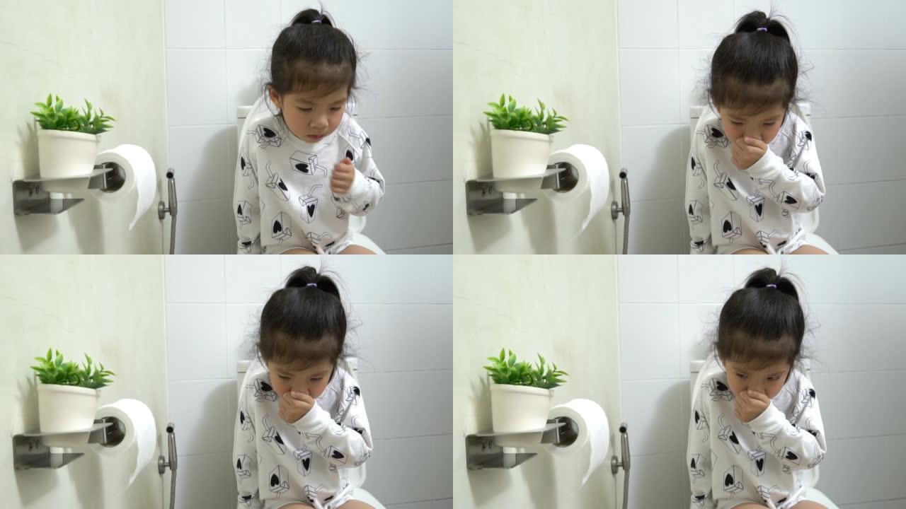 亚洲小女孩坐在白色浴室的抽水马桶上，学习如何自己使用马桶，为父母教孩子，KidsHealth概念，慢