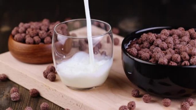 将牛奶倒入装有巧克力球的玻璃杯中，用作干早餐