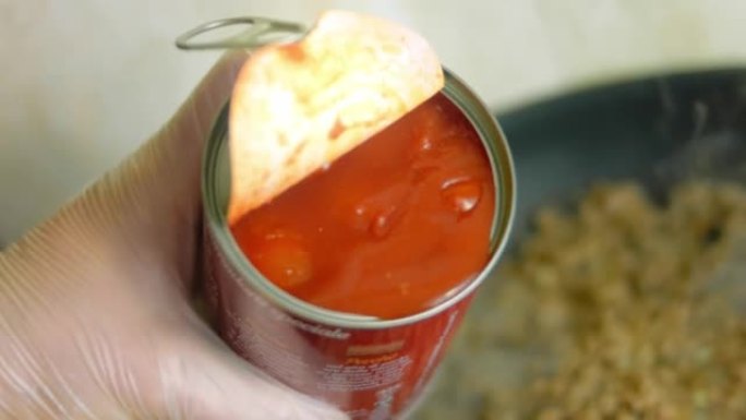 将少量罐装的西红柿倒在油炸的香肠配料上