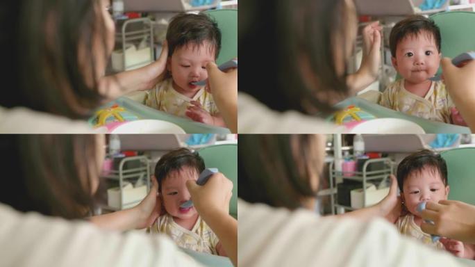 可爱的亚洲宝宝在椅子上吃婴儿食品。