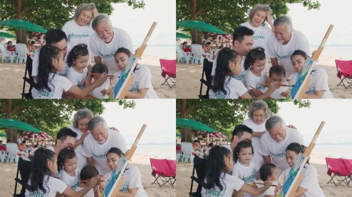 快乐的亚洲家庭穿着快乐的志愿者衬衫培养孩子学习如何在海滩上保护自然。绘画活动，志愿者精神，人和生态观