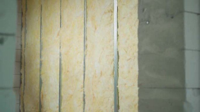 玻璃棉铺设在空心框架石膏板隔板中。光滑的相机变焦到建筑工地的裸露墙壁