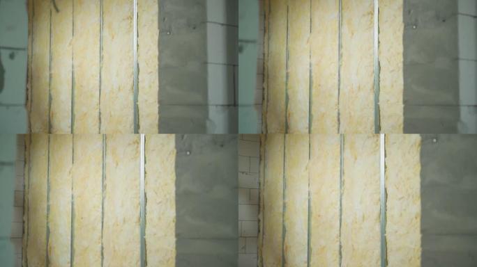 玻璃棉铺设在空心框架石膏板隔板中。光滑的相机变焦到建筑工地的裸露墙壁