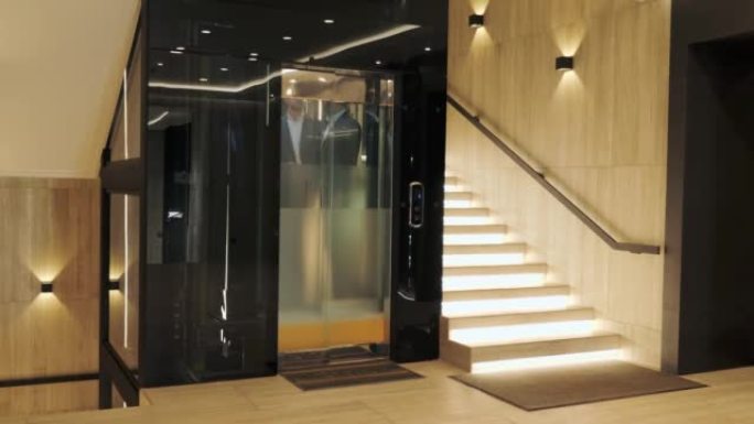 一群商人正在现代玻璃电梯中前进。成功人士乘电梯到商务中心的顶部。时尚的男人和女人在谈论电梯内部的项目