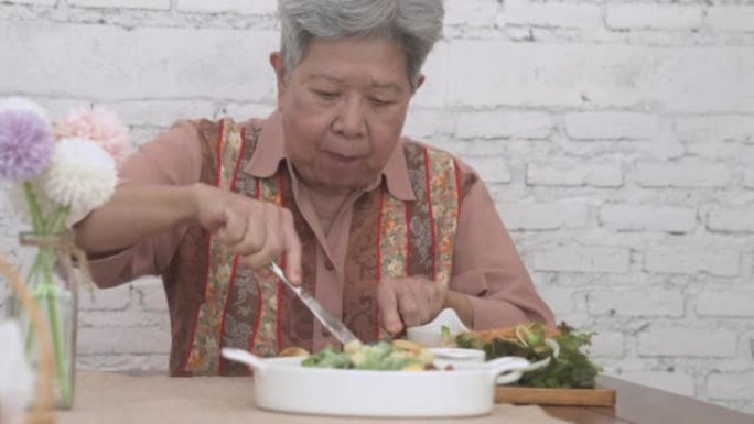 老年老年妇女吃烤猪排牛排食物。成熟的退休生活方式