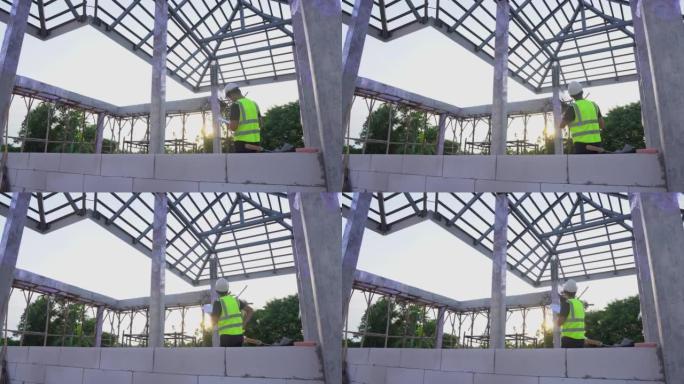 一名工程师技术人员使用蓝图纸观察房屋建筑现场下方的钢屋顶结构。